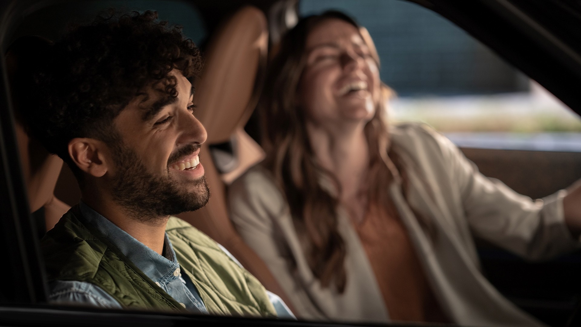 Mann und Frau sitzen in MINI Fahrzeug und lachen. Mann und Frau sitzen in MINI Fahrzeug und lachen.